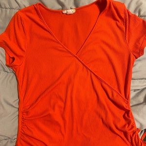 Cute peach colored shirt has strings on the bottom sides and cute design (Glitz)